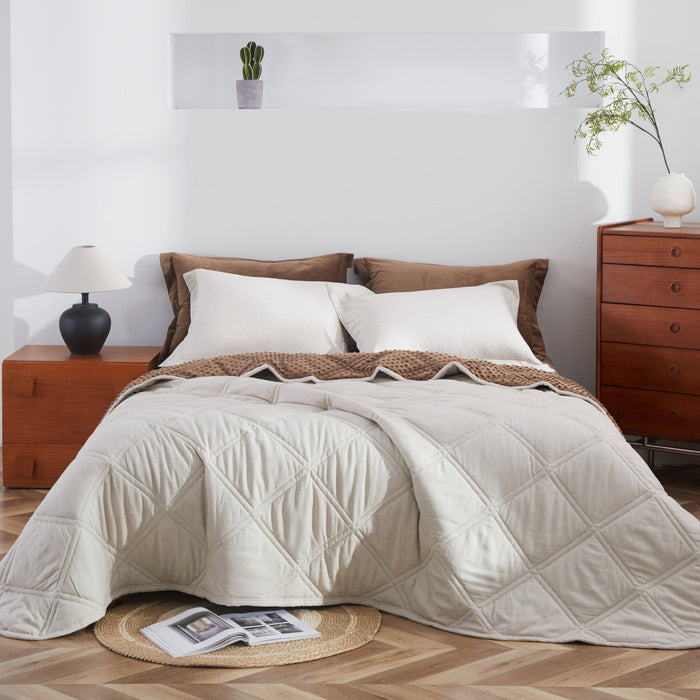 Neatly made bed with beige comforter in a bedroom setting.