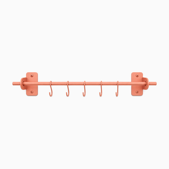 Etta Utensil Rack in matte coral finish with wall mounts and six hooks, a minimalist, durable metal wall shelf bracket for organizing utensils.