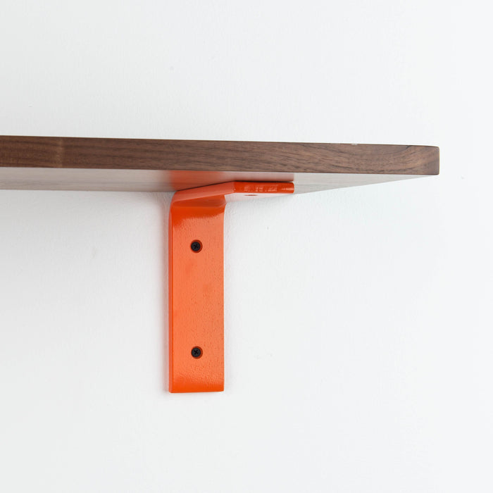 Leif Walnut Wall Shelf with smooth walnut glue-up and bright orange metal L bracket for bold floating shelf support