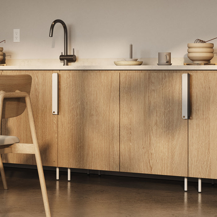 Lowell Round Cabinet Foot Hardware supporting natural wood cabinetry with a minimalist kitchen scene featuring modern faucet and neutral decor.