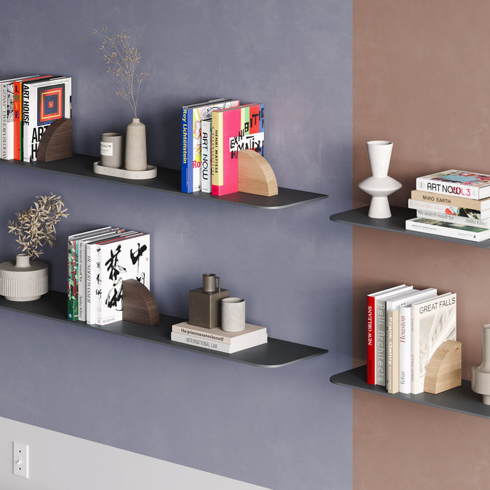 Image of a three colored wall with four tungsten tromso radius shelves, holding books and a vases. Two Maggie Radius (white oak finish) and two maggie Radius (walnut finish) bookends are positioned holding the books.