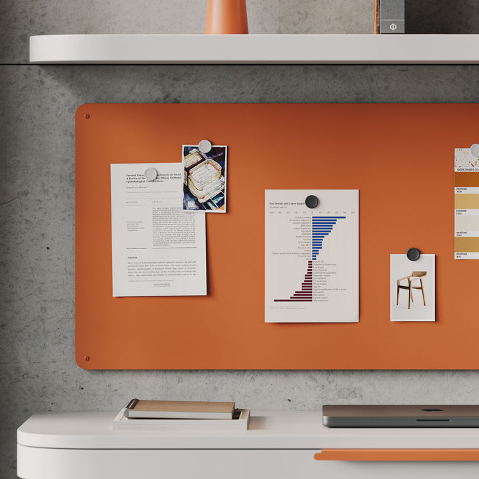 Mosey Magnet Board in vibrant orange mounted on wall with notes and photos pinned above white modern desk setup