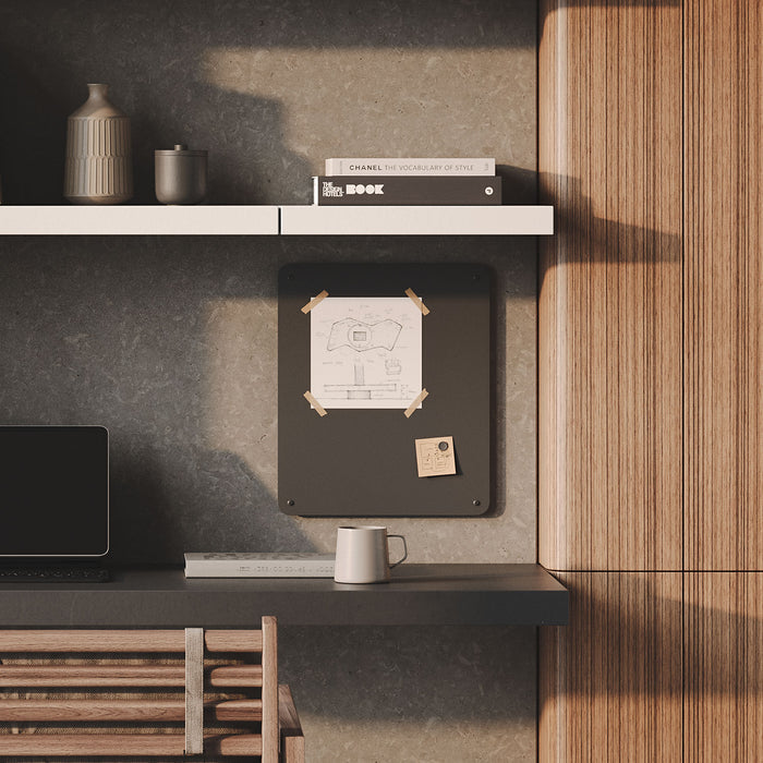 Mosey Magnet Board in dark steel mounted on wall above modern desk with books, mug, and laptop by Shelfology