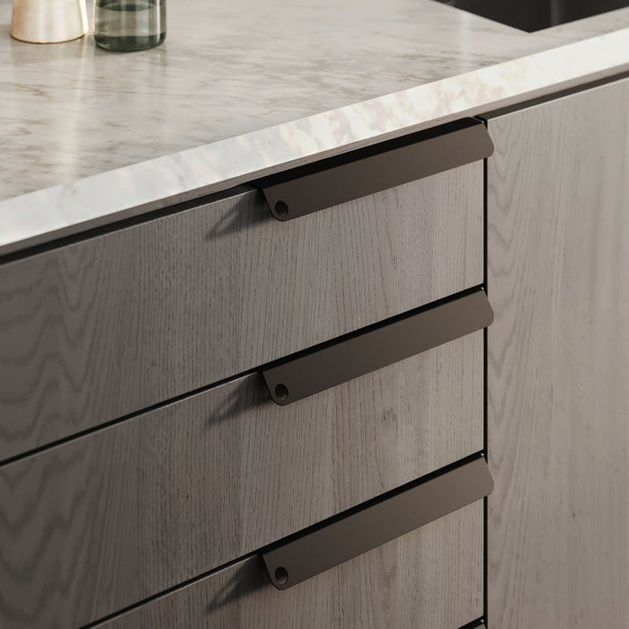 Peek Cabinet Pull in dark steel finish on light wood drawers for modern kitchen hardware and functional organization