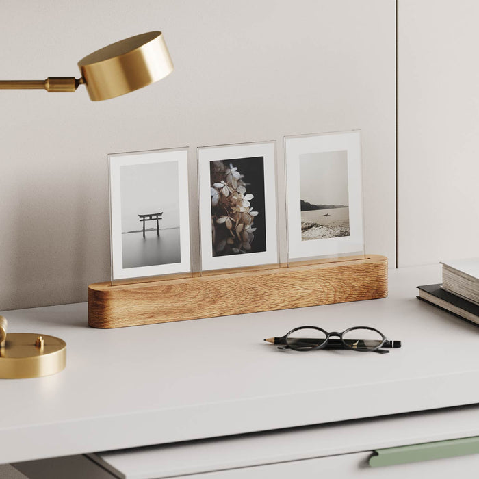 Pill Picture Holder with solid hardwood base displaying three photos on minimalist white desk with brass lamp and glasses