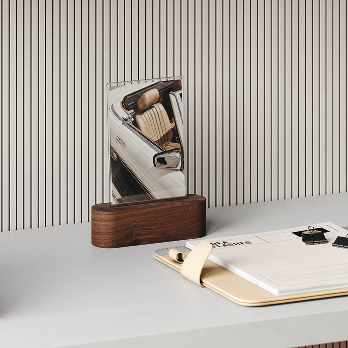 Pill Picture Holder with solid hardwood base displaying photo on clean desk with striped wall background and organizer folder nearby