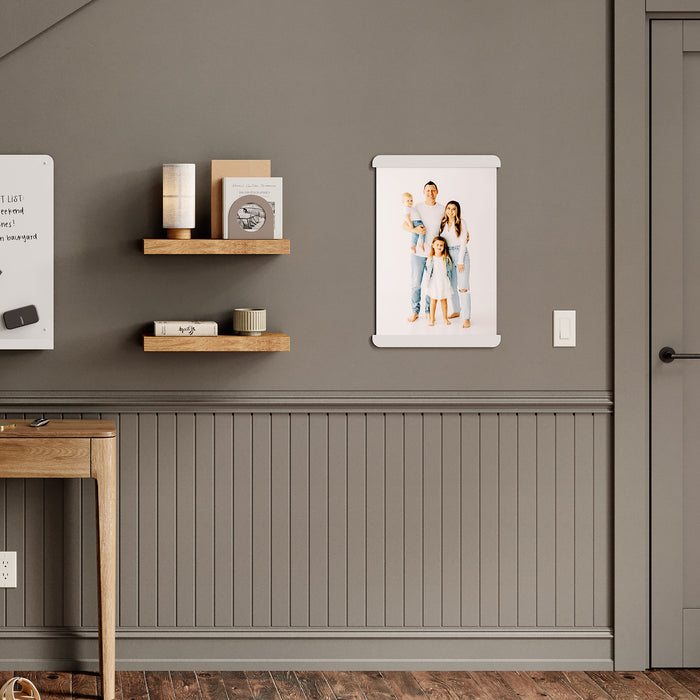 RADius Magnetic Print Hanging System in matte white steel displaying a family portrait on a taupe wall above wood floating shelves