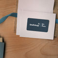 Shelfology eGift Card in white envelope with blue ribbon on wood surface for gifting organization solutions