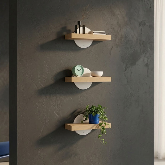 Three Shortie Deux Wall Shelves mounted on a dark textured wall displaying decorative items including books, a clock, a bowl, and a potted plant in a minimalist, functional design that maximizes wall space.