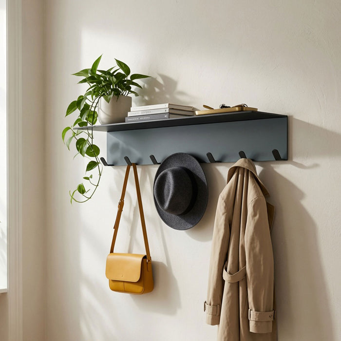 Splendid Shelf + Coat Hooks in matte black metal with five hooks holding a tan bag, gray hat, and beige coat beneath a shelf displaying a potted plant and books