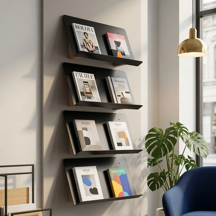 The Edit Book +Magazine Display mounted on a wall in a modern living space featuring minimalist black metal shelves showcasing magazines next to a window with natural light.