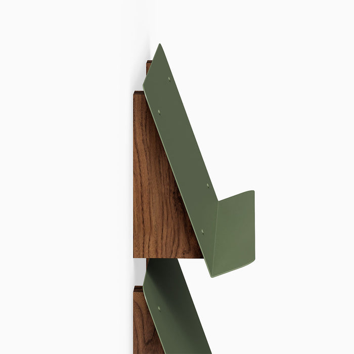 The Edit Book +Magazine Display features a sleek walnut wood back with angled olive green metal supports, designed for minimalist wall organization.