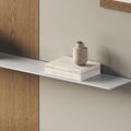 Tromso Steel Floating Shelf in gray steel mounted on wall with minimalist ceramic vase and stacked books by Shelfology
